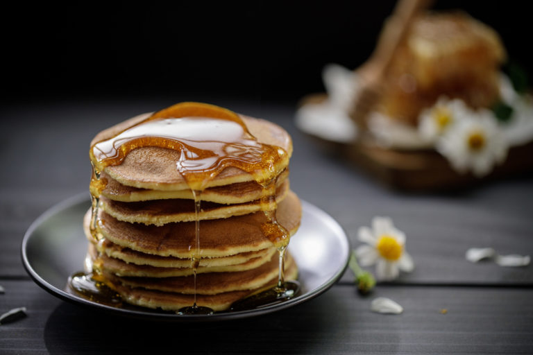 Honey overflowing on the stack of pancakes